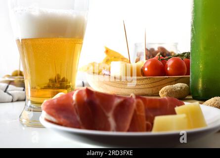 Details mit einem Glas Bier und Vorspeisen auf einem weißen Tisch und isoliertem Hintergrund. Vorderansicht. Stockfoto