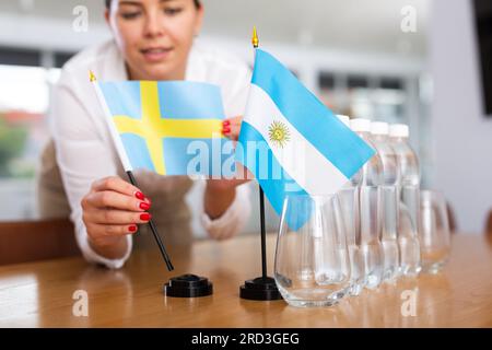 Ein nicht wiedererkennbares Mädchen setzt vor internationalen Verhandlungen Zwergflaggen von Argentinien und Schweden Stockfoto