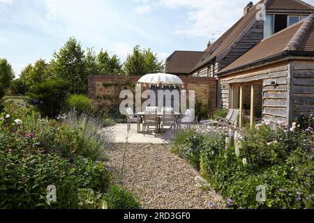 Essbereich im Freien mit Tisch, Stühlen und Sonnenschirm. Manor Barn, Faringdon, Vereinigtes Königreich. Architekt: Keine, 2015. Stockfoto