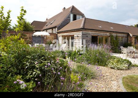 Essbereich im Freien mit Tisch, Stühlen und Sonnenschirm. Manor Barn, Faringdon, Vereinigtes Königreich. Architekt: Keine, 2015. Stockfoto