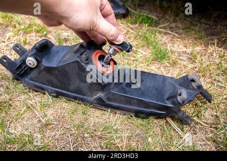 Austausch einer durchgebrannten Glühlampe in einem Autoscheinwerfer durch eine LED-Leuchte. Stockfoto