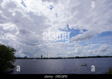 Hamburg, Deutschland. 18. Juli 2023. Dichte Wolken passieren die Segelboote und Tretboote in der Außenalster. Kredit: Marcus Brandt/dpa/Alamy Live News Stockfoto