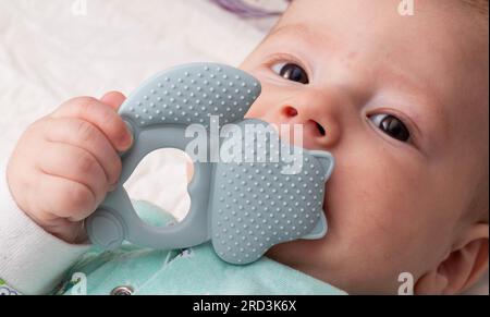 Ein kleiner Junge spielt mit einem Beißring während des Ausbruchs der ersten Zähne. Juckreiz und Zahnfleischschmerzen am ersten Zahn. Stockfoto