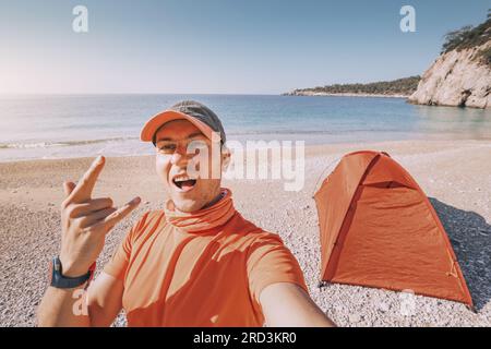 Abenteuerlust entlang der Lykischen Straße, während ein Mann Selfie-Fotos vor einem Campingzelt am Sandstrand an einer Seeküste macht Stockfoto