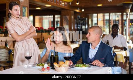 Freundin trifft untreuen Mann im Restaurant Stockfoto