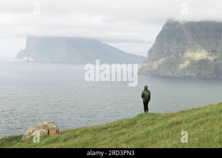 Lonely Tourist in der Nähe von kleinen See schaut auf nebligen Inseln im Atlantik von kalsoy Island, Färöer, Dänemark. Landschaftsfotografie Stockfoto
