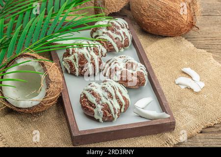 Profiteroles wählen Gebäck mit Kokosnusscreme in tropischem Stil. Palmenblätter, süßes gesundes Dessert, flach liegend, Kopierraum Stockfoto