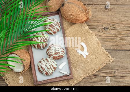 Profiteroles wählen Gebäck mit Kokosnusscreme in tropischem Stil. Palmenblätter, süßes gesundes Dessert, flach liegend, Draufsicht Stockfoto