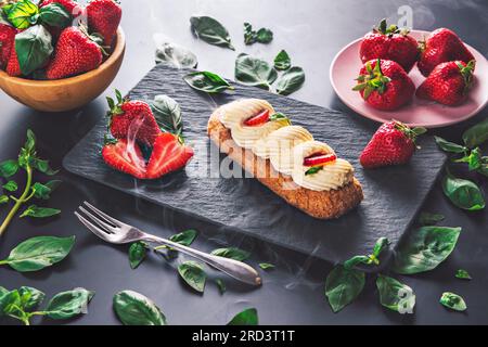 französischer eclair mit Schokolade und fruchtiger Erdbeercreme oder süßen italienischen Profiteroles und frischen, saftigen Erdbeeren, Essen frisch im Sommer Backgrou Stockfoto