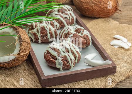 Profiteroles wählen Gebäck mit Kokosnusscreme in tropischem Stil. Palmenblätter, süßes gesundes Dessert, flach liegend, Nahaufnahme Stockfoto