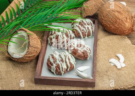 Profiteroles wählen Gebäck mit Kokosnusscreme in tropischem Stil. Palmenblätter, süßes gesundes Dessert, flach liegend, Nahaufnahme Stockfoto