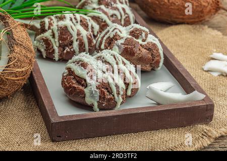 Profiteroles wählen Gebäck mit Kokosnusscreme in tropischem Stil. Palmenblätter, süßes gesundes Dessert, flach liegend, Nahaufnahme Stockfoto