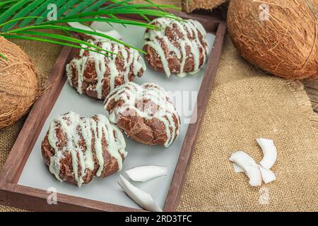 Profiteroles wählen Gebäck mit Kokosnusscreme in tropischem Stil. Palmenblätter, süßes gesundes Dessert, flach liegend, Kopierraum Stockfoto