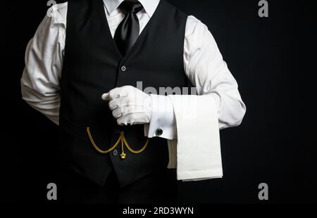 Porträt von elegantem Butler oder Kellner in schwarzer Weste und weißen Handschuhen, die gerne behilflich sein möchten. Stockfoto