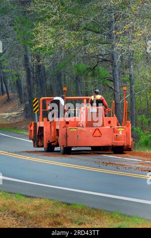 Das Arkansas Highway Department arbeitet an einer schmalen Landstraße. Große Maschinen pressen Kies an Ort und Stelle, damit der Straßengrader seine Arbeit erledigen kann. Stockfoto