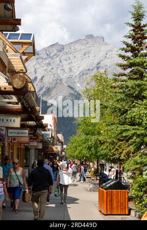 BANFF, KANADA - 5. JULI 2023: Touristen, die die Stadt Banff im Banff National Park mit Cascade Mountain im Hintergrund genießen. Der Ort ist ein Meter Stockfoto