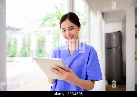 Portrait des glücklichen Arztes oder Krankenschwester, die die Tablette hält, die den Patienten im Krankenhaus oder Pflegeheim besucht, Ärztin Pflegekraft trägt Uniform Stockfoto