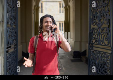 Männlicher Student telefoniert am Mobiltelefon außerhalb des Universitätsgebäudes in Oxford UK Stockfoto
