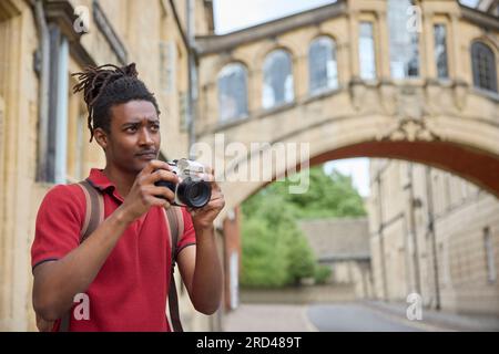 Junger Mann, Der Im Urlaub Unterwegs Ist Und Fotos Mit Der Kamera Macht, Wenn Er Die Sehenswürdigkeiten In Oxford Besichtigt Stockfoto
