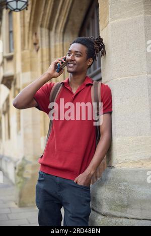 Männlicher Student telefoniert am Mobiltelefon außerhalb des Universitätsgebäudes in Oxford UK Stockfoto
