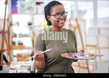 Du bist ein Kunstwerk. Freigestellte Aufnahme einer jungen Frau mit einer Künstlerpalette in einem Kunstatelier. Stockfoto
