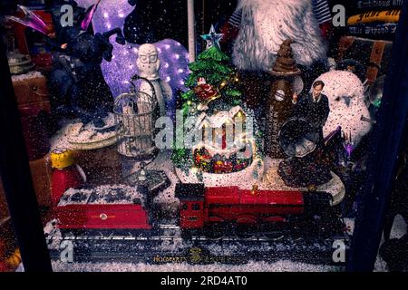 Fenster des Weihnachtsgeschäfts, Fenster mit verschneiter Weihnachtsszene, Regentropfen und Reflexionen am Schaufenster Stockfoto