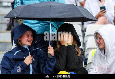 Zuschauer suchen sich Schutz unter einem Schirm, während der dritte One Day International der Women's Ashes Series auf dem At Cooper Associates County Ground, Taunton, regnet. Bilddatum: Dienstag, 18. Juli 2023. Stockfoto