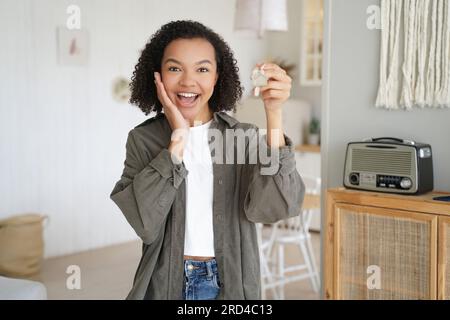 Ein fröhliches Mädchen kauft ein neues Haus, hält Schlüssel, feiert den Homecoming. Immobilienwerbung. Stockfoto