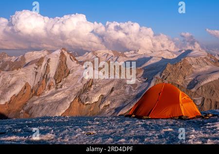 Zeltlager auf dem Eisgipfel mit atemberaubendem Blick auf die Berge bei Sonnenuntergang; Konzept für Outdoor-Aktivitäten in freier Wildbahn Stockfoto