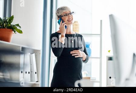 Sie ist bereit, ihren Kunden zu helfen, wann immer sie es brauchen. Aufnahme einer schwangeren Geschäftsfrau, die mit einem Handy in einem Büro spricht. Stockfoto