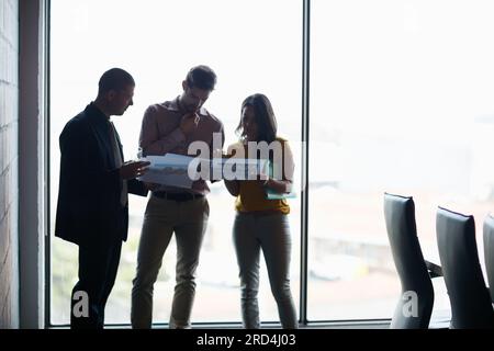 Sie sollen sich auf das Meeting vorbereiten. Kurze Aufnahme von drei Geschäftsleuten, die sich im Sitzungssaal unterhalten. Stockfoto