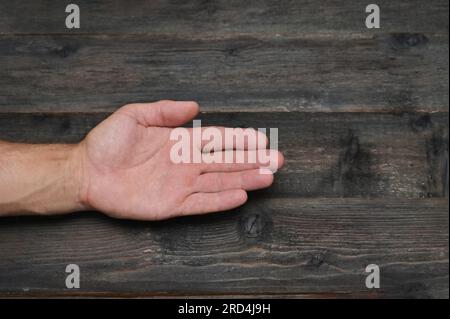 Die Hand eines Mannes auf einem Hintergrund aus Holzbrettern. Nahaufnahme der Handfläche. Stockfoto