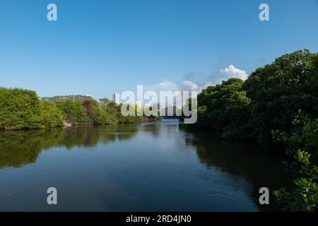 Calm River überquert den Mangrovenpark in Cartagena de Indias, Kolumbien, mit dunklem Rauch, der bei Sonnenuntergang von den weißen Gebäuden kommt Stockfoto