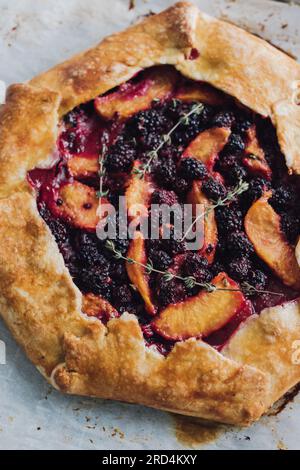 Pfirsich, Brombeere, Thymian-Galette, Nahaufnahme auf Pergamentpapier direkt aus dem Ofen Stockfoto