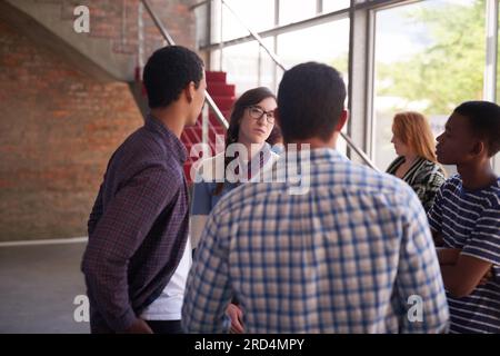 Zwischen den Pausen aufholen. Freigestellte Aufnahme einer Gruppe von Studenten, die zwischen den Klassen abhängen. Stockfoto