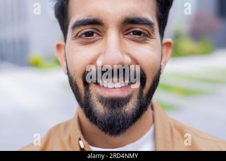 Nahaufnahme Foto eines jungen Hindu-Studenten, lächelnder Mann, der in die Kamera schaut, Geschäftsmann außerhalb des Bürogebäudes, der ein Hemd trägt. Stockfoto