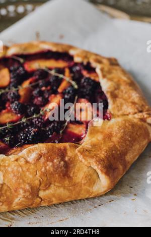 Pfirsich, Brombeere, Thymian-Galette, Nahaufnahme auf Pergamentpapier direkt aus dem Ofen Stockfoto