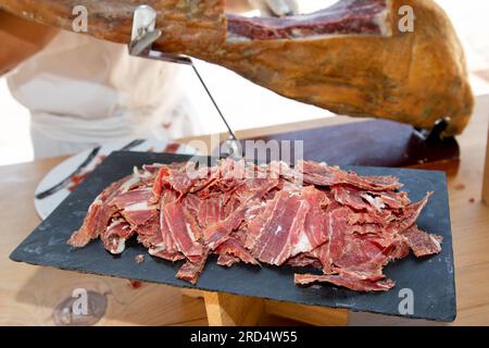 Roter Schweineschinken, geschnitten von einem Handkoch professioneller Schnitzer von ganzen Knochen in serrano-Schinken Stockfoto