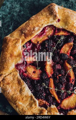 BlackBerry, Pfirsich, Thymian-Galette auf grünem Marmorbrett Stockfoto