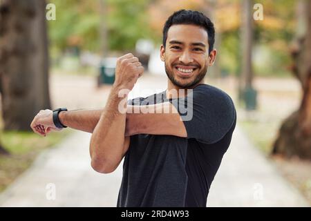 Glücklicher asiatischer Mann, Porträt und Arme strecken in Fitness, die sich für das Laufen, Training oder Training im Park vorbereiten. Männlicher Mensch oder Läufer mit Lächeln Stockfoto