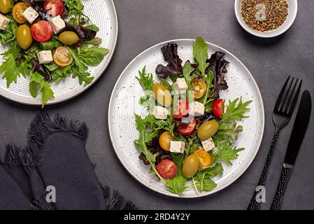 Lebensmittelfotografie von Fetasalat; Gemüse; Tomaten; Oliven; Salat; Spinat, Rucola, mizuna, Käse; Blätter; Bio; Zutaten; Scheibe; Vitamin; Vegetation Stockfoto