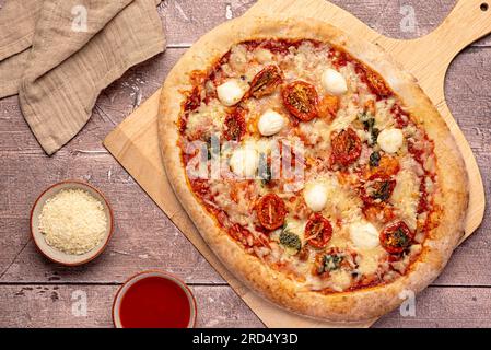 Lebensmittelfotografie von Pizza; Mozzarella, getrocknet, Tomate, Basilikum, Pesto; Parmesan; Käse; Tomaten; Soße; Oregano; würzig; Hintergrund; Mahlzeit; Lebensmittel Stockfoto