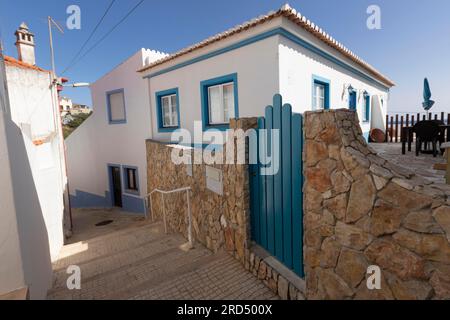 Blaues Holztor vor einem Wohnhaus in einer Gasse in Praia do Burgau, Bezirk Faro, Algarve, Portugal Stockfoto