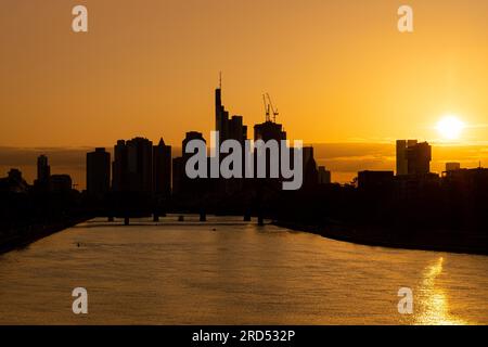 Die Sonne geht hinter der Frankfurter Bank-Skyline, der Deutschen herrnbrücke, Frankfurt am Main, Hessen, Deutschland, unter Stockfoto