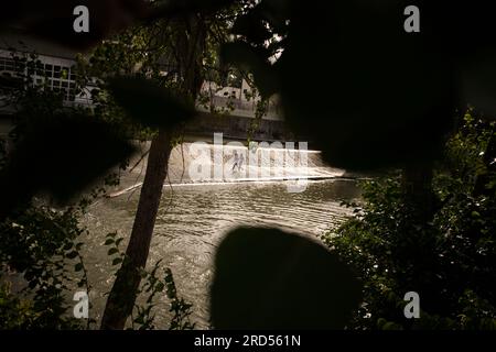 Pamplona, Spanien. 18. Juli 2023. Zwei junge Menschen laufen unter einem Wasserfall in einem beliebten Badegebiet am Fluss Arga in Pamplona, Nordspanien. (Foto: Sergio Martín/SOPA Images/Sipa USA) Guthaben: SIPA USA/Alamy Live News Stockfoto