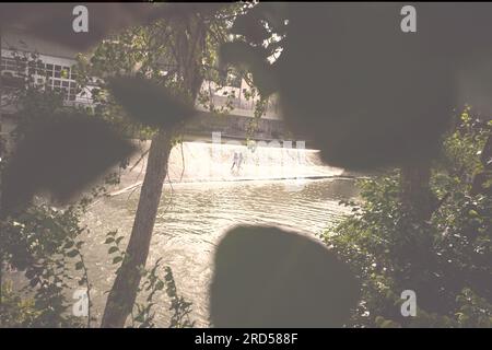 Pamplona, Spanien. 18. Juli 2023. Zwei junge Menschen laufen unter einem Wasserfall in einem beliebten Badegebiet am Fluss Arga in Pamplona, Nordspanien. (Kreditbild: © Sergio MartÃ-N/SOPA Images via ZUMA Press Wire) NUR REDAKTIONELLE VERWENDUNG! Nicht für den kommerziellen GEBRAUCH! Stockfoto