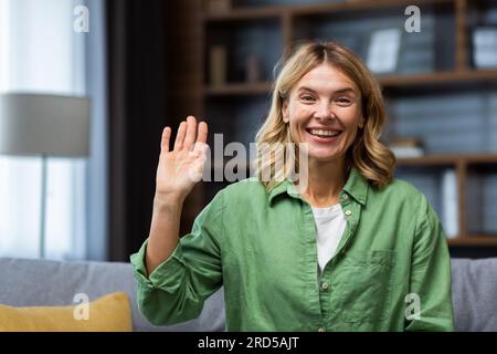 Webcam-Ansicht, Online-Videoanruf, ältere Frau, die spricht und sich die lächelnde Webcam ansieht, die im Wohnzimmer auf dem Sofa zu Hause sitzt. Stockfoto