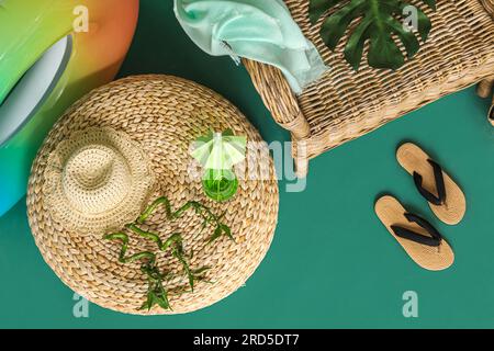 Strandaccessoires, ein Glas Cocktail und Bambuszweige auf farbigem Hintergrund Stockfoto