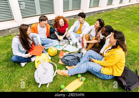 Glückliche Studentenfreunde, die sich zusammen auf dem Campus-Gras entspannen Stockfoto