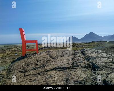 Herrlicher sonniger Tag und roter Holzstuhl zwischen Hoefn und Egilsstadir in Island. Standort: Stokksnes Cape, Island, Europa. Stockfoto